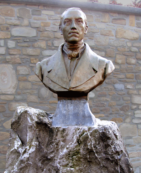 Photographie du buste en bronze posé sur une grosse pierre brute